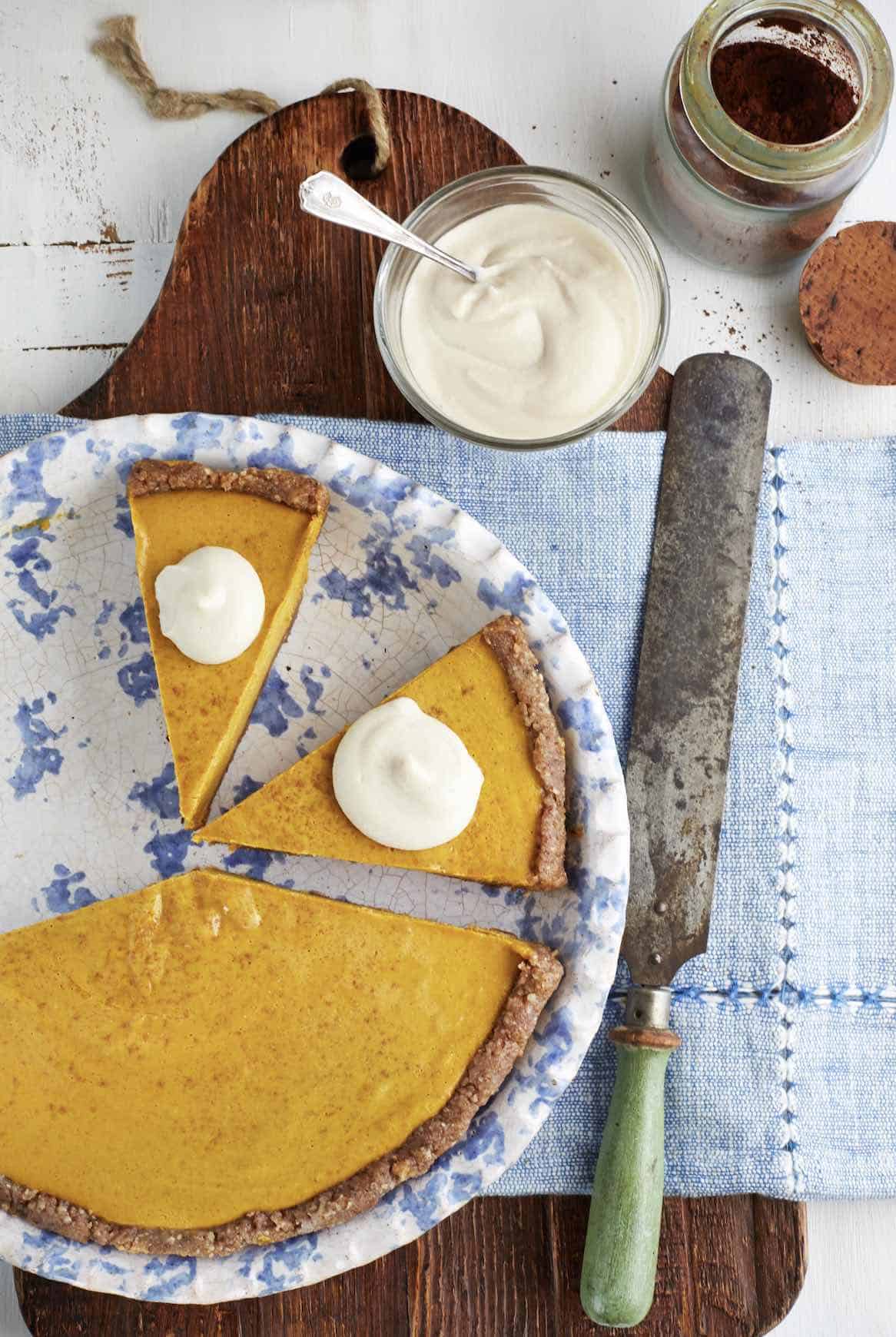 A pumpkin pie, with a slice missing, beautifully presented on a plate.