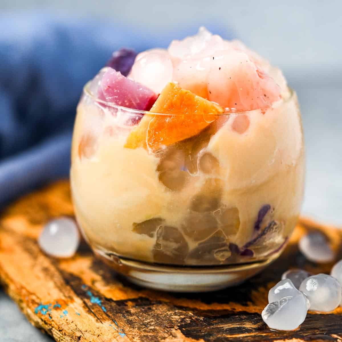 A glass filled with buber cha cha containing a variety of tapioca jellies, steamed root vegetables, and coconut porridge.