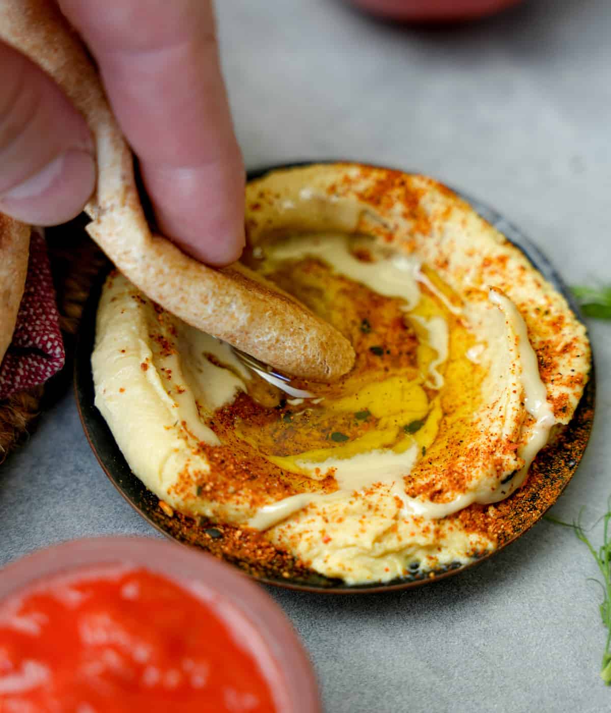 Hummus being eaten with a torn off piece of pita bread.