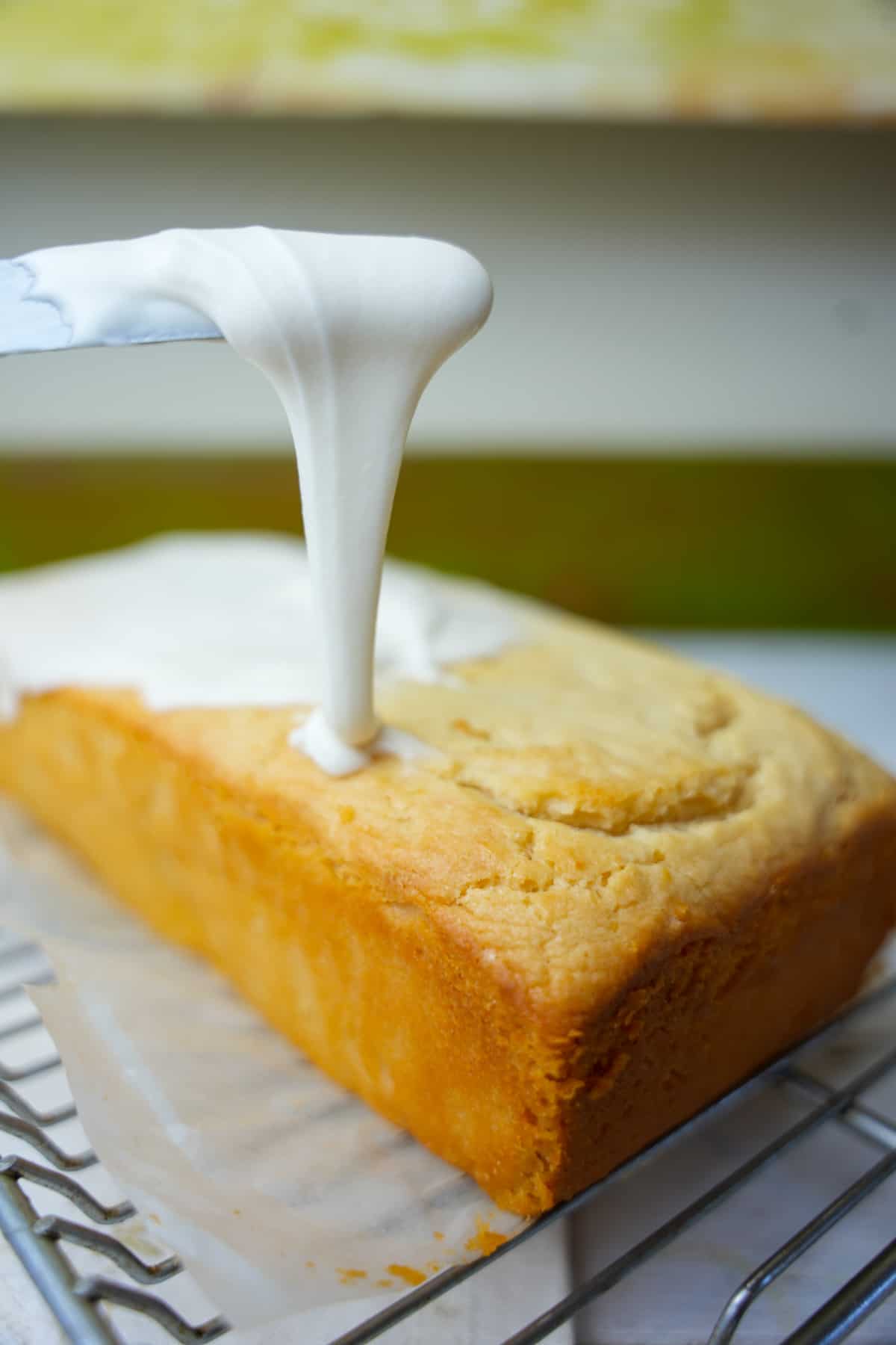Spreading frosting onto a pound cake cooling on a wire rack