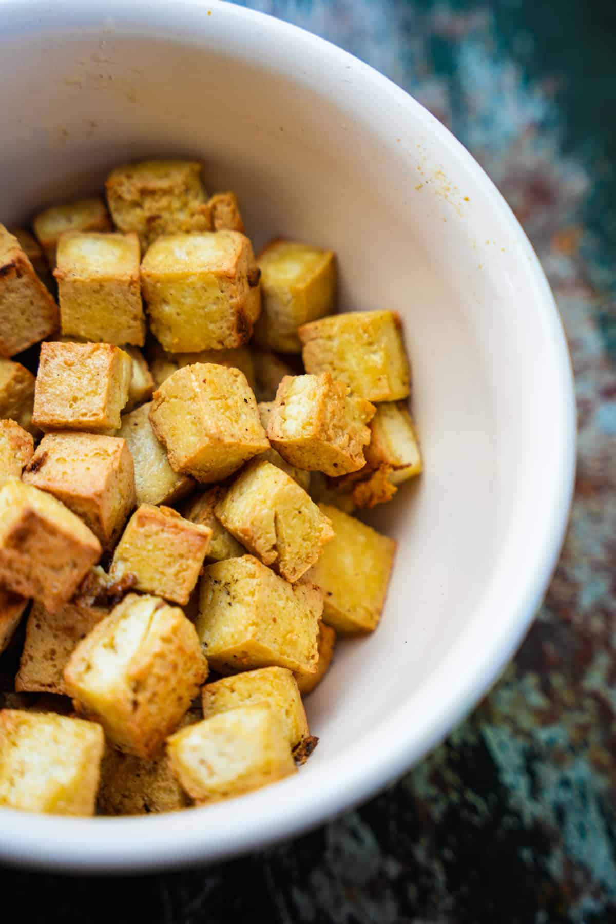 Tofu placed in a bowl aside while the rest of the dish cooks.