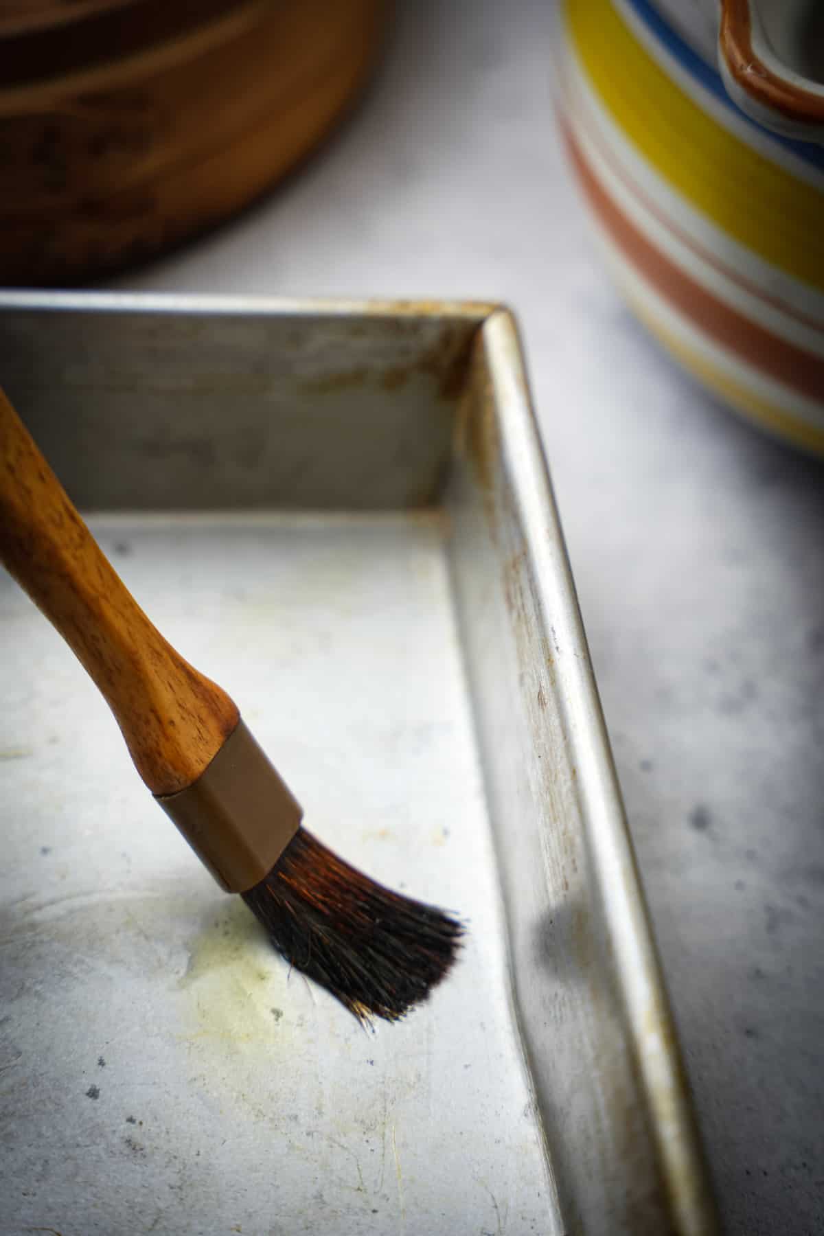 Preparing the pan to steam the batter in by brushing it with oil.