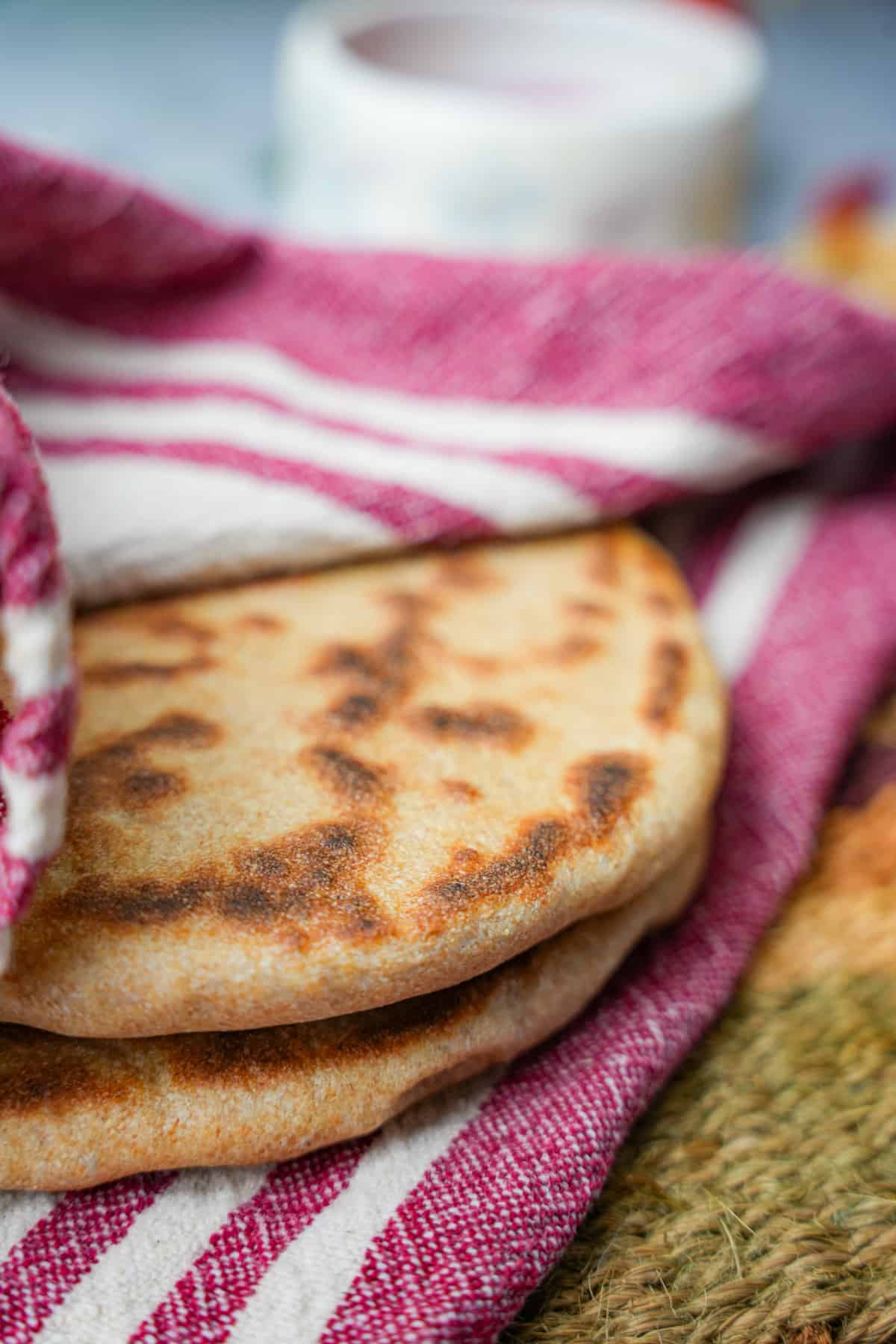 Finished pita breads are kept warm wrapped in a kitchen towel.