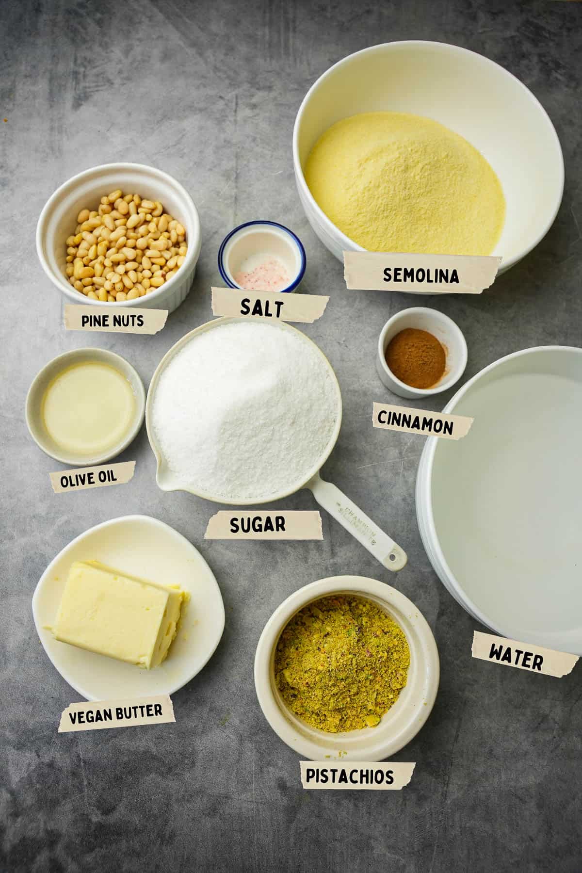 Ingredients for making Irmik helvasi measured out in bowls and labeled with the names of the ingredients.