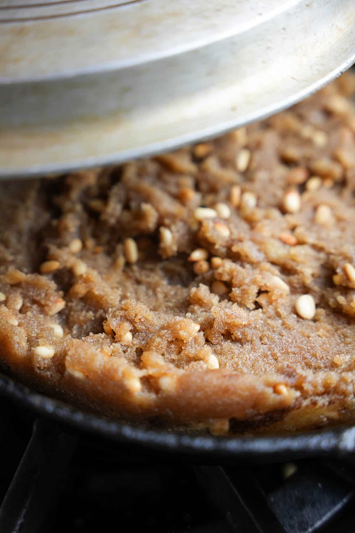 A lid is put over the cooked halva so that it steams as it cools in the pan.