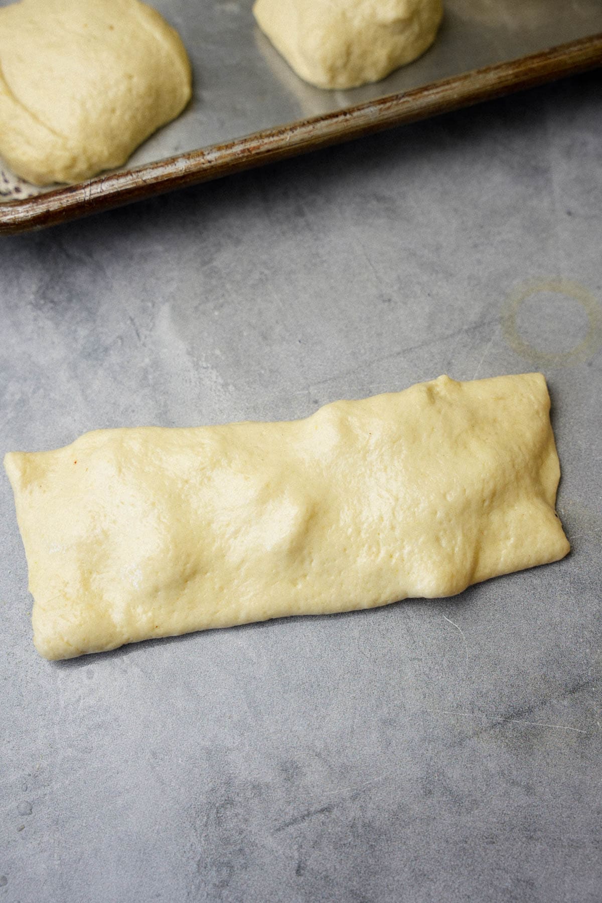 Butter filled dough is folded over into a rectangle shape.