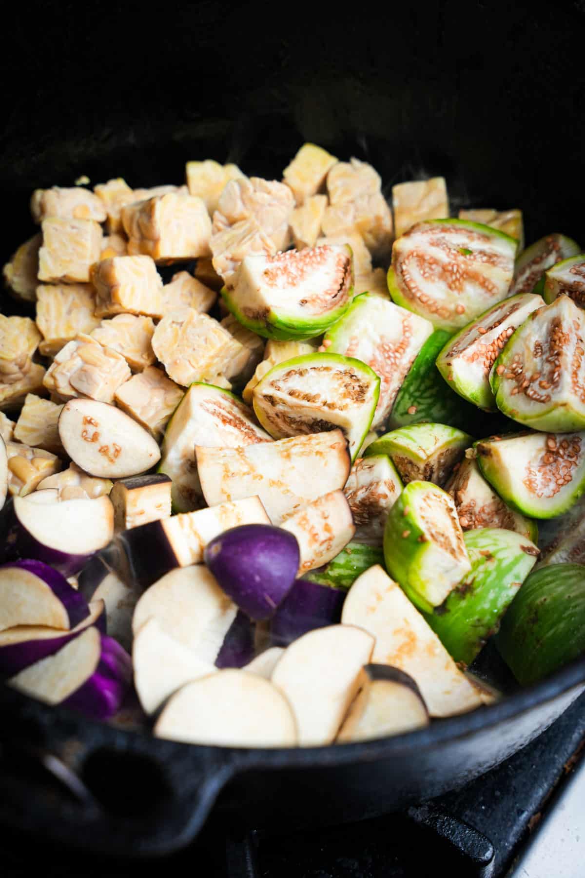 Tempeh, thai eggplant, and chinese eggplant are cooked in a cast iron dutch oven.