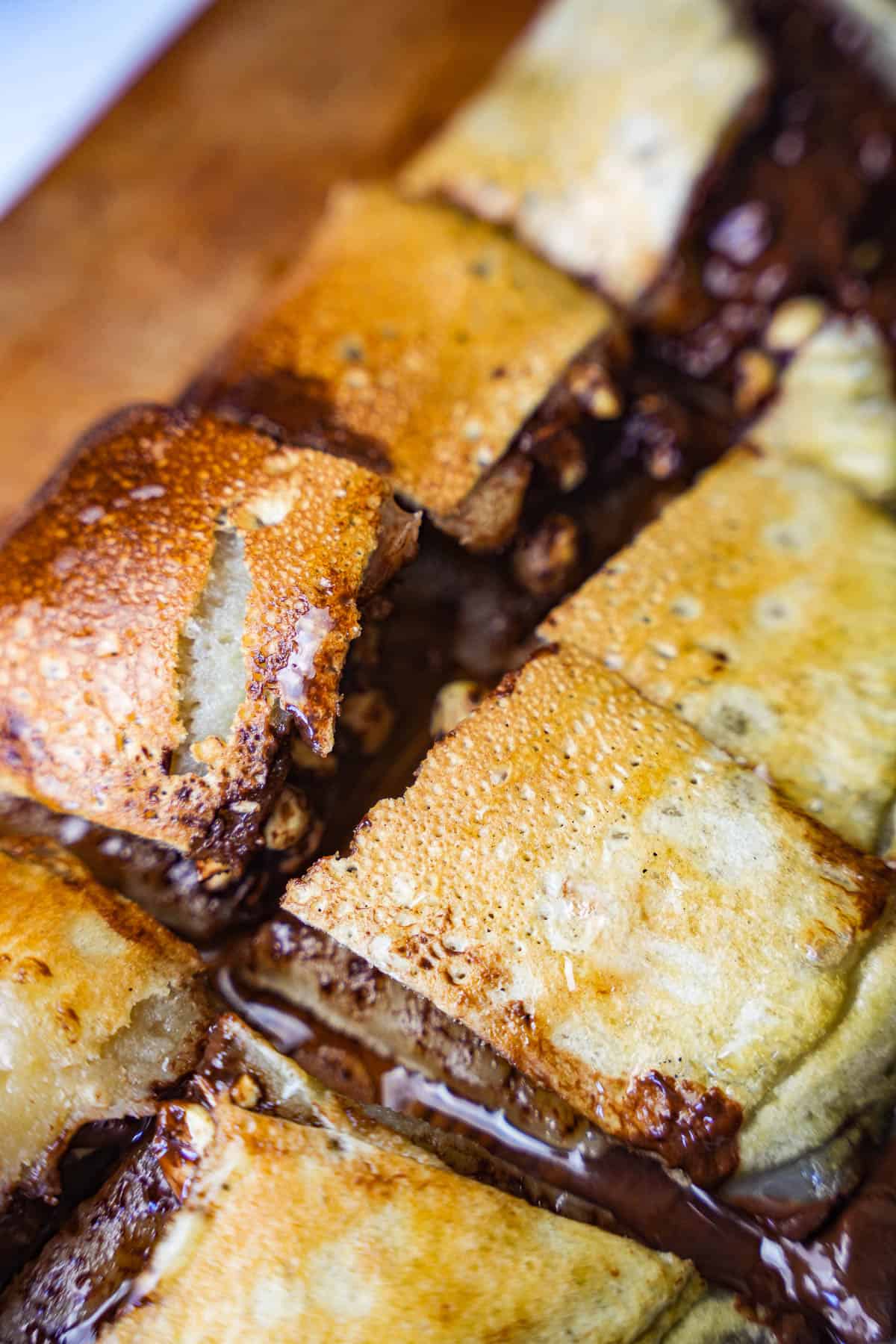 The martabak is cut into small rectangular pieces. It is wet from being drizzled with condensed coconut milk.