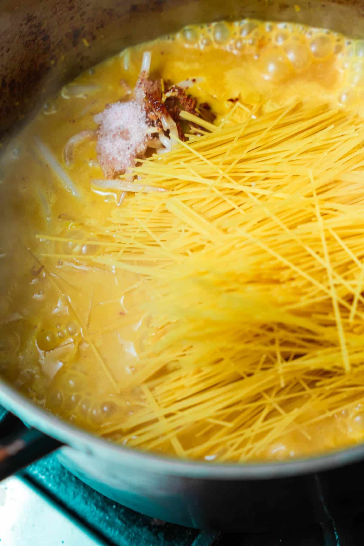 Angel hair pasta and seasonings are added to the pot of curry.