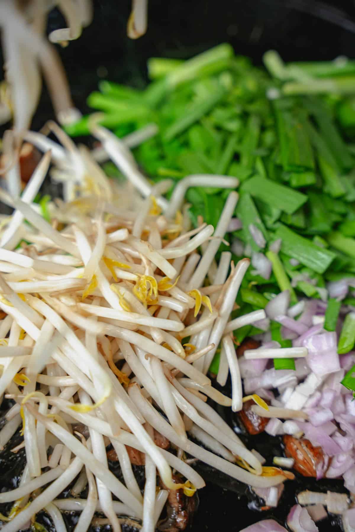 Beansprouts are added to the pan.