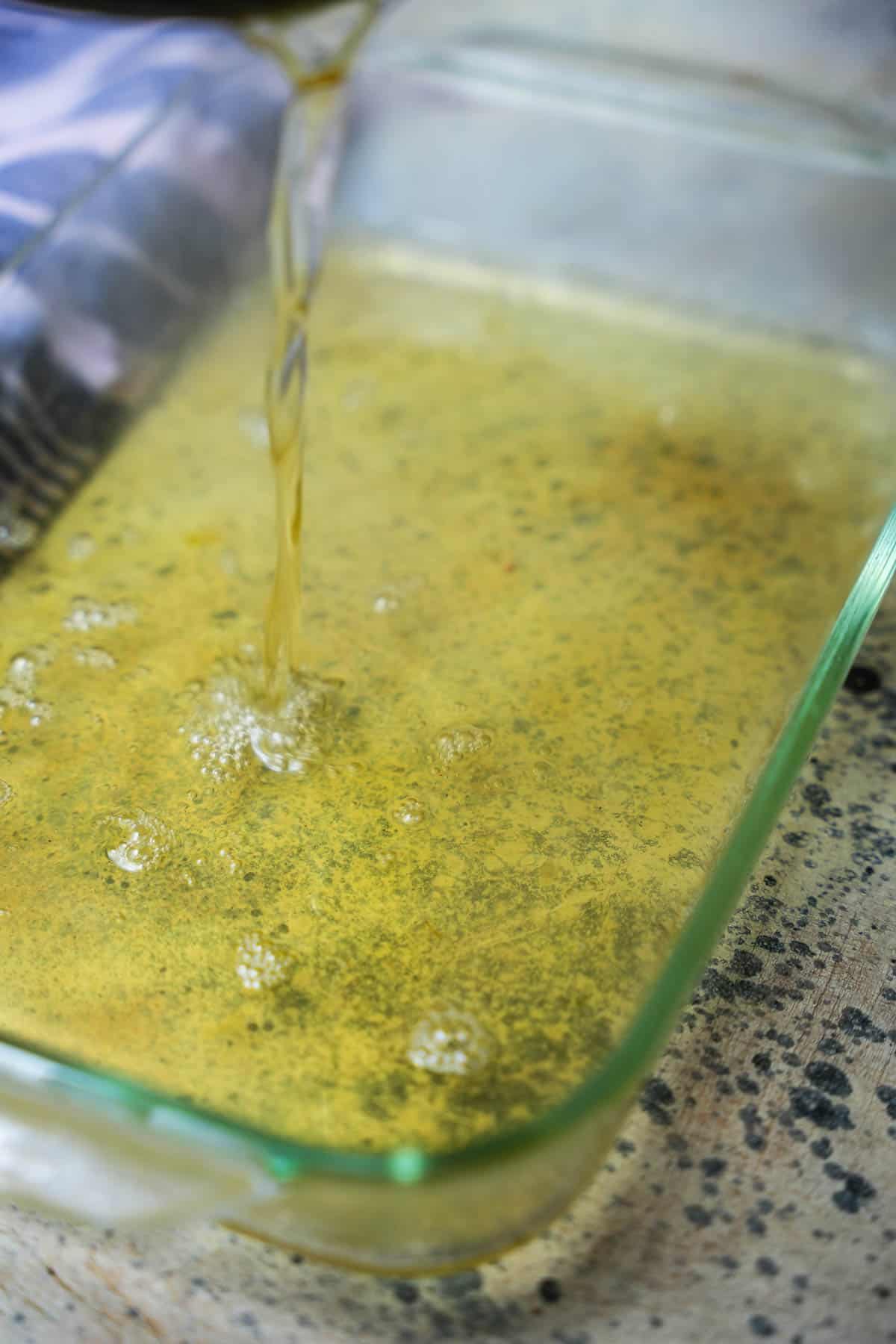 The cooked pandan jelly liquid is poured into a pyrex pan to cool and set up.