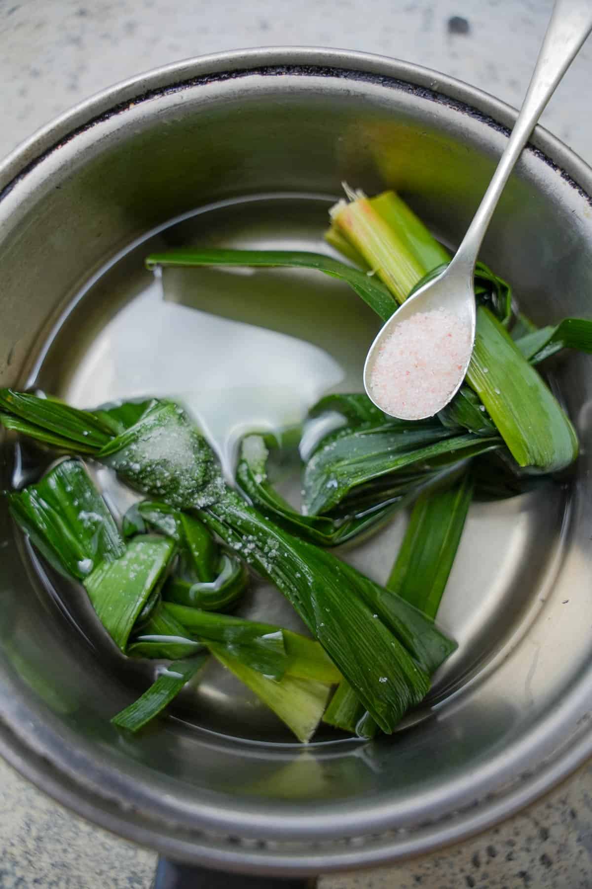 pandan leaves, sugar water and salt are added to a saucepan to be cooked into the initial liquid to form the pandan jelly