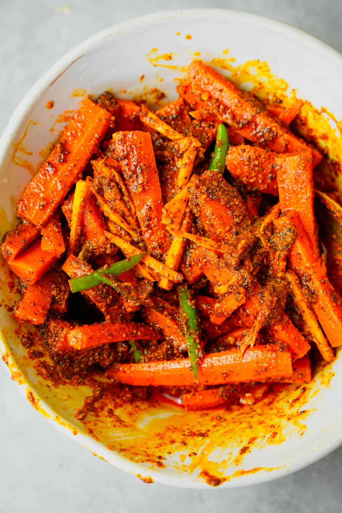 Carrot pickle is mixed in a white ceramic bowl.