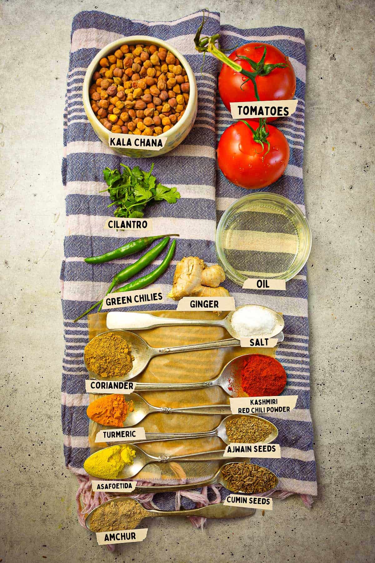 The ingredients for making kala chana are measured out and labeled on a cloth topped table.