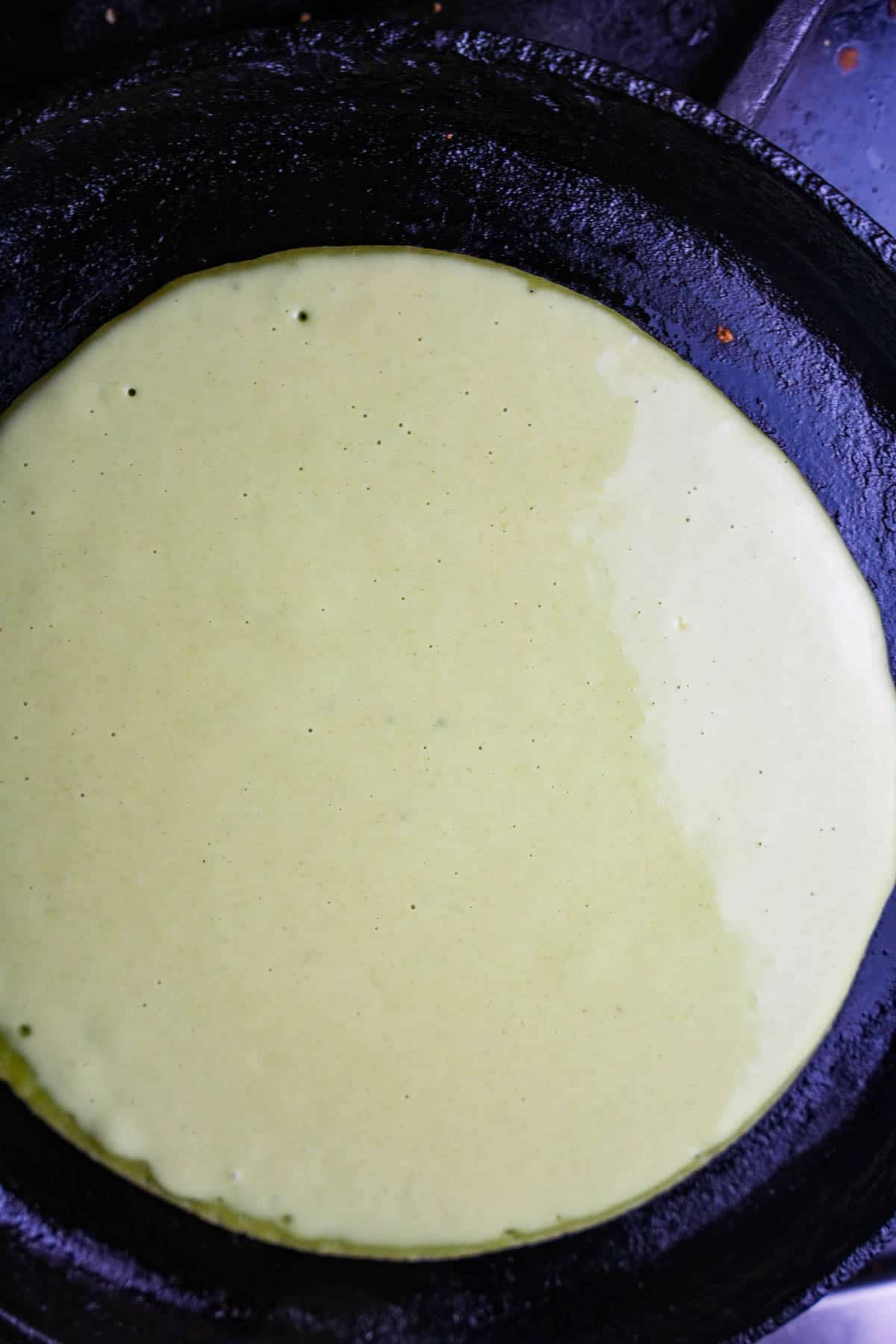 a skillet with a green batter cooking in it.