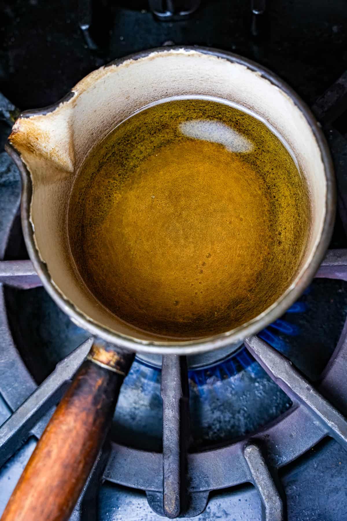 a saucepan with a mustard oil is heating on top of a stove.