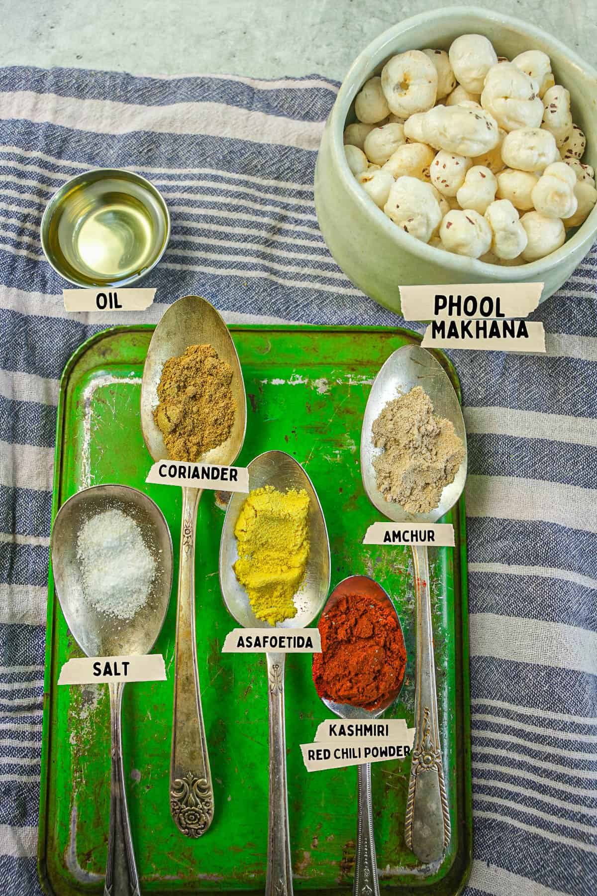 A green tray with the ingredients for phool makhana measured out and labeled on it.