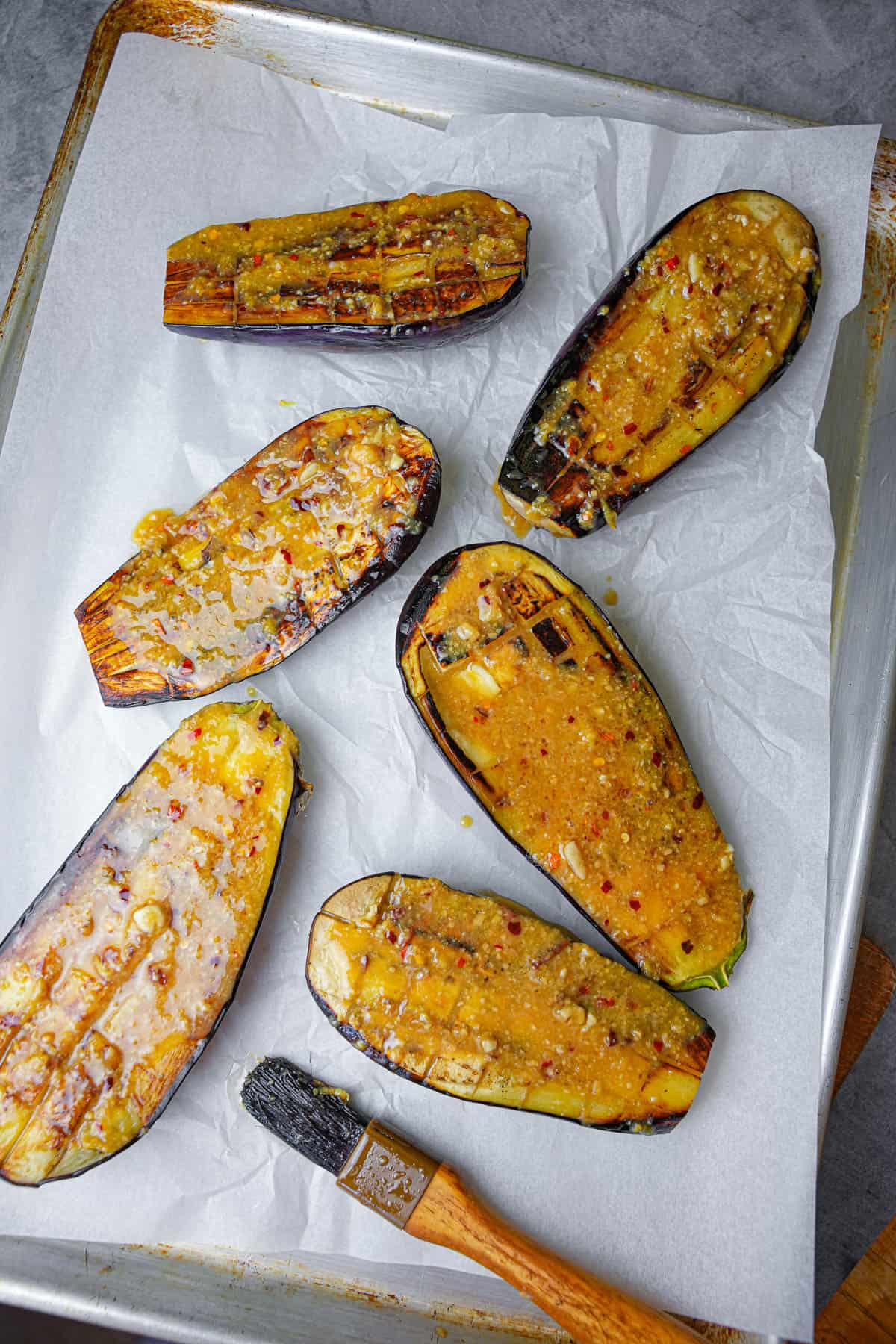 Eggplant is brushed with miso glaze before going into the oven on a parchment paper lined baking pan.