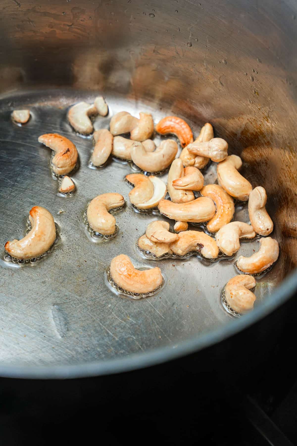 Cashews are being fried in a pan on a stove.