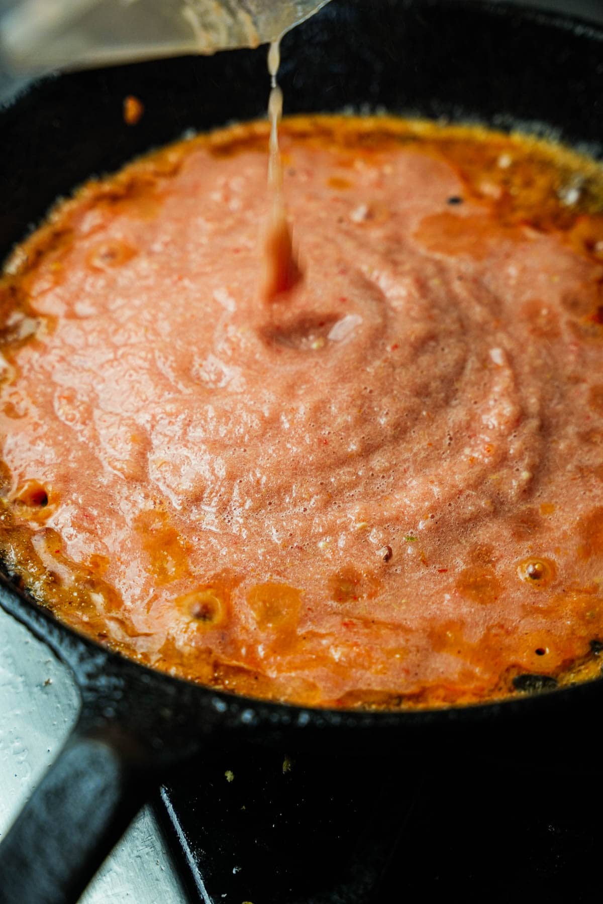 The spice paste is cooking in hot oil in a cast iron skillet.