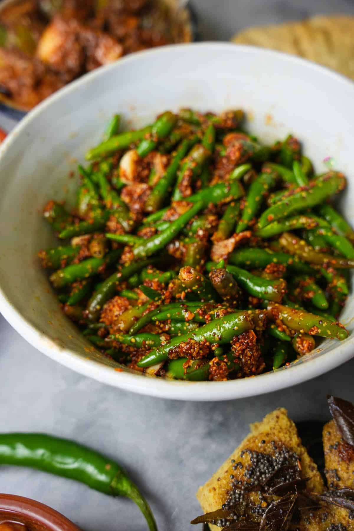 a bowl of green chilies with spices and dhokla.