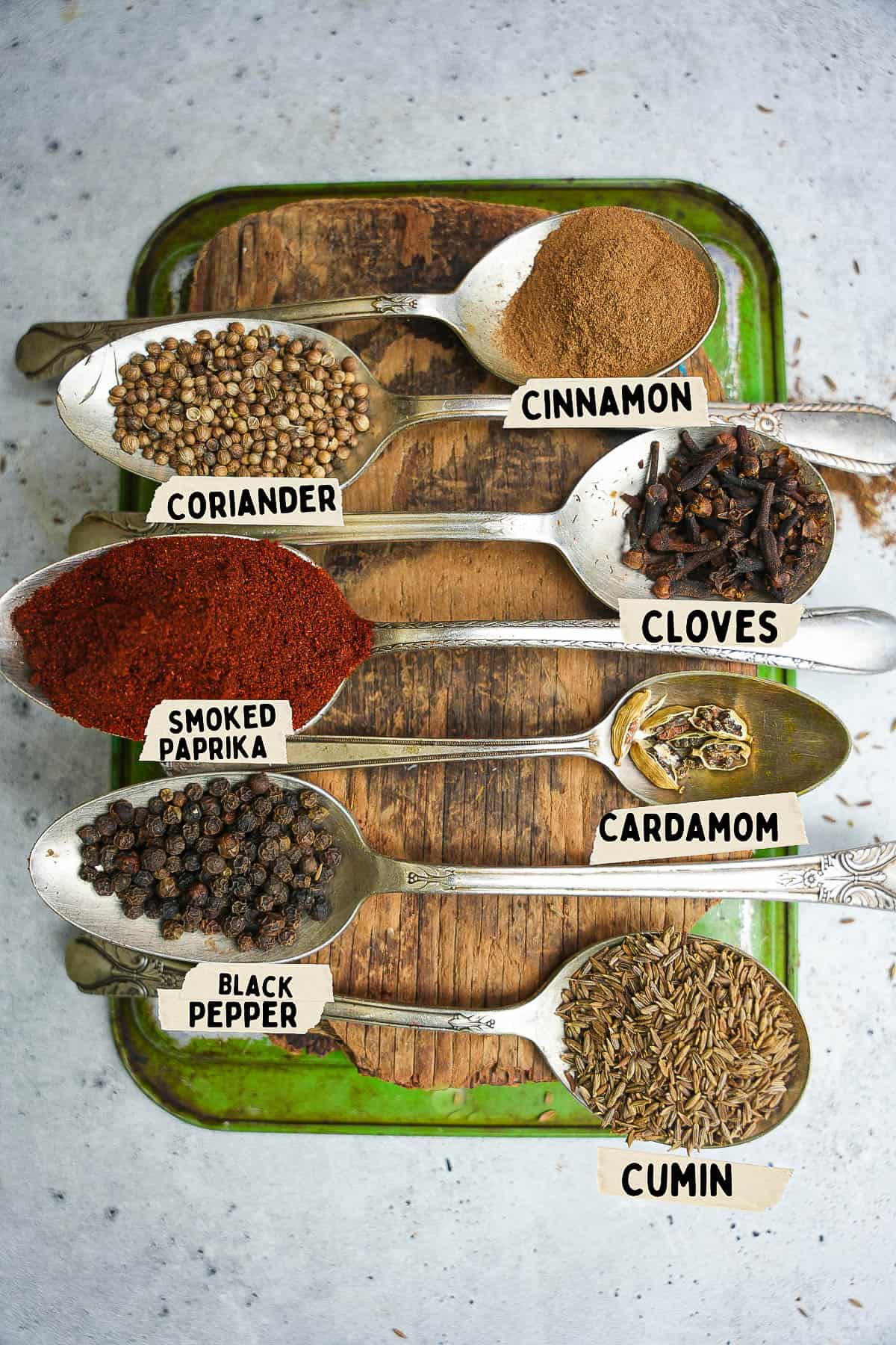 Spices for making baharat in spoons are labeled on a tray.