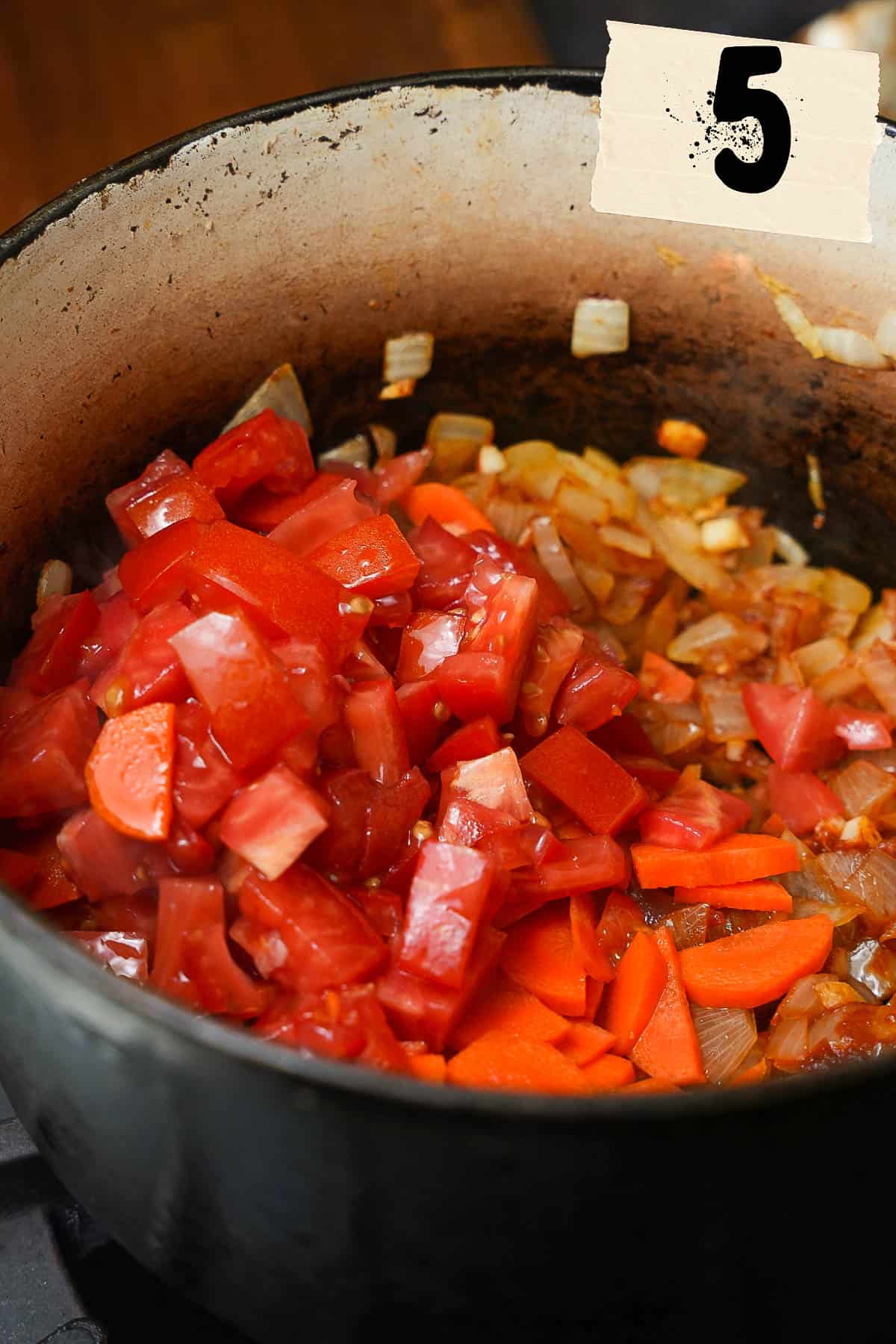 Tomatoes and carrots added to the pot on the stove.