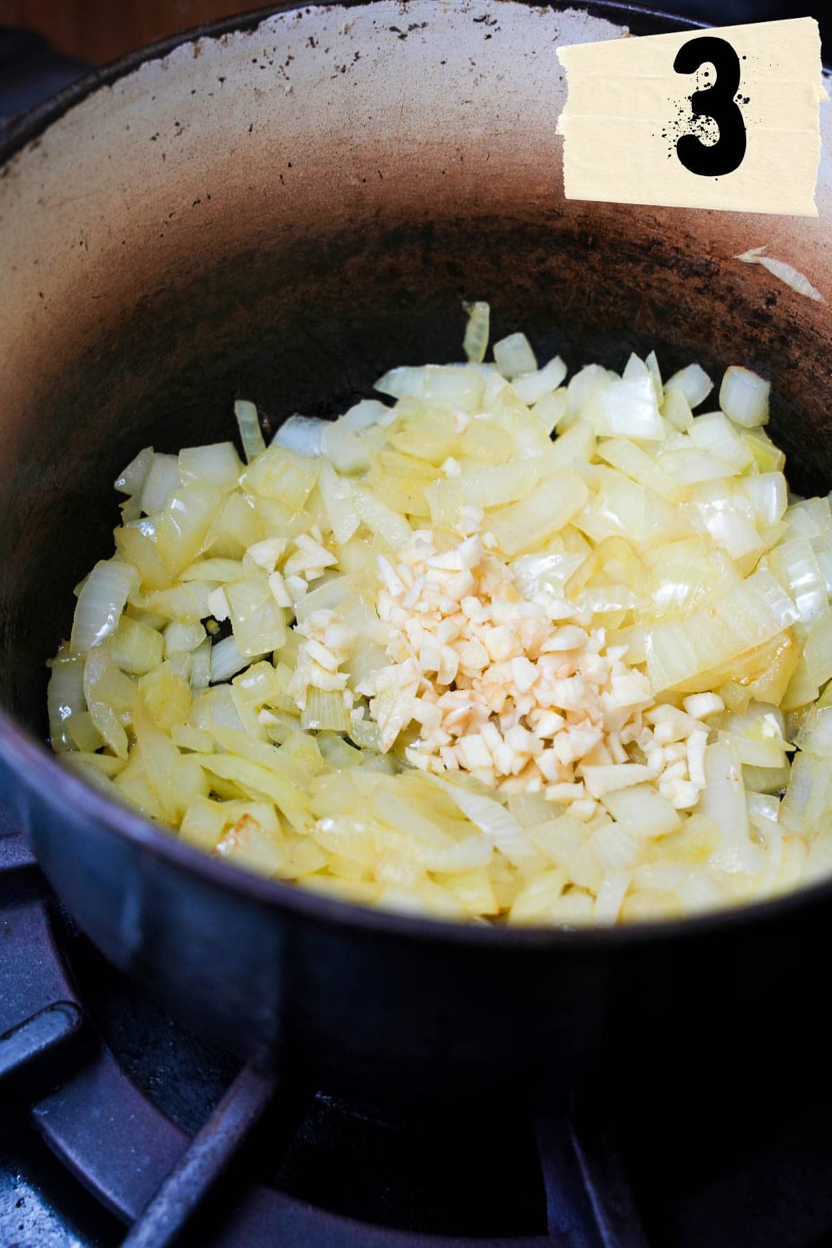Garlic and onions sauté in a pot on the stove.