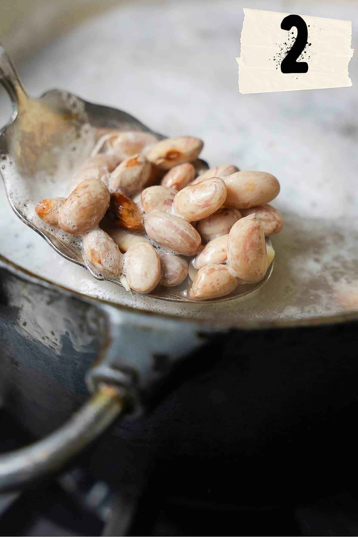 Cooking borlotti beans in a pot on a stove.