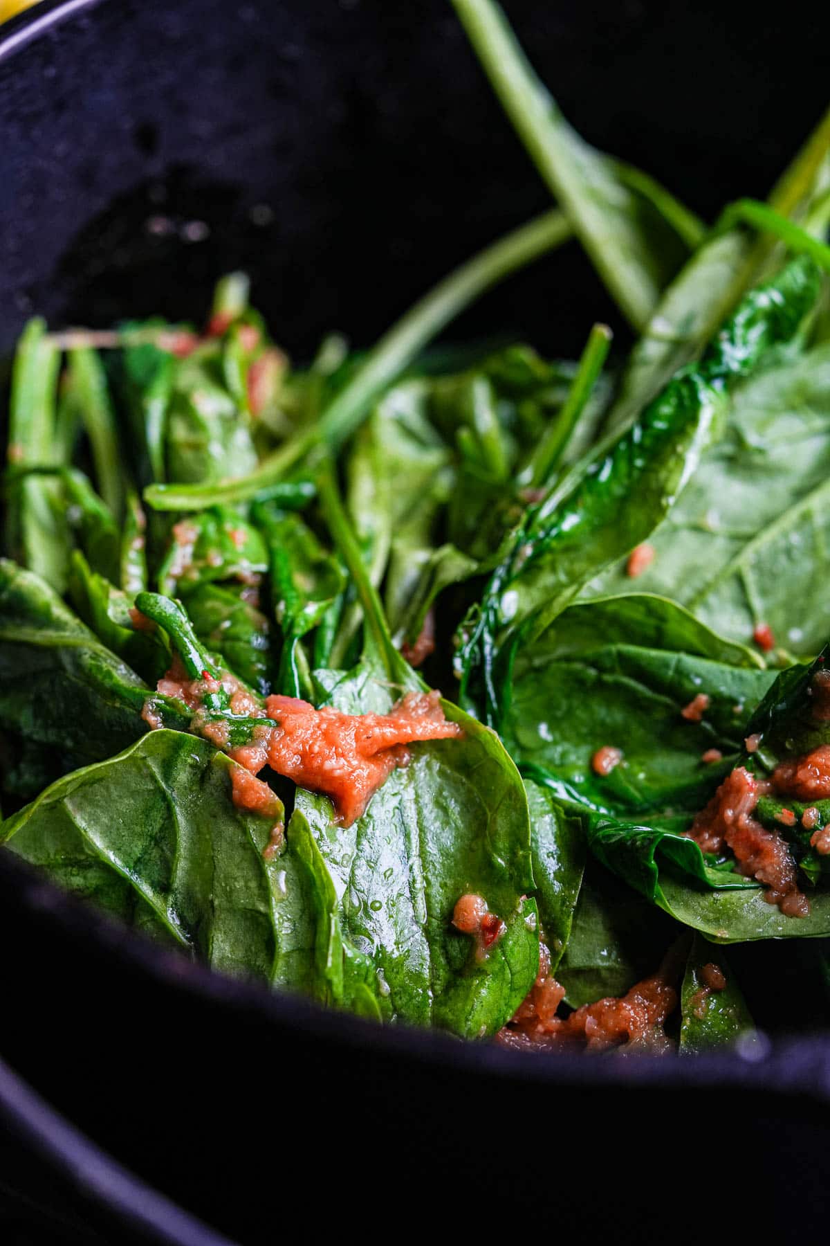 Spinach in a skillet with sambal.