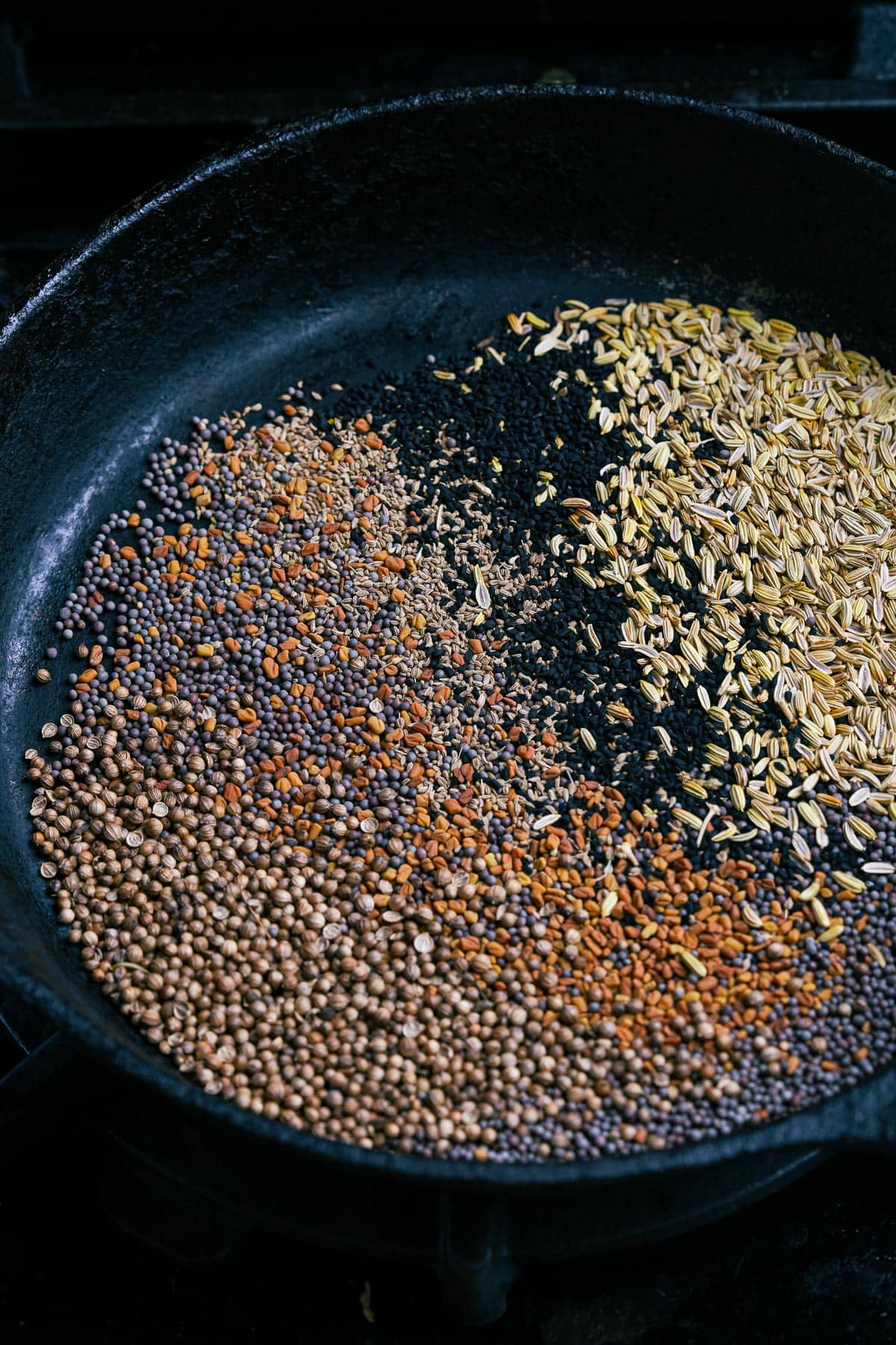 A frying pan with seeds dry roasting in it.