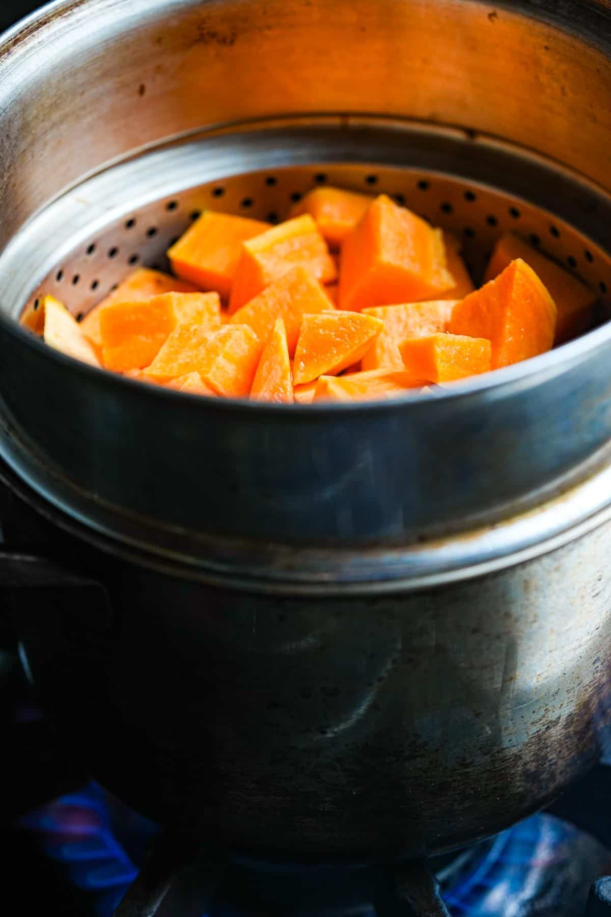 A pot of steaming sweet potatoes on a stove top.