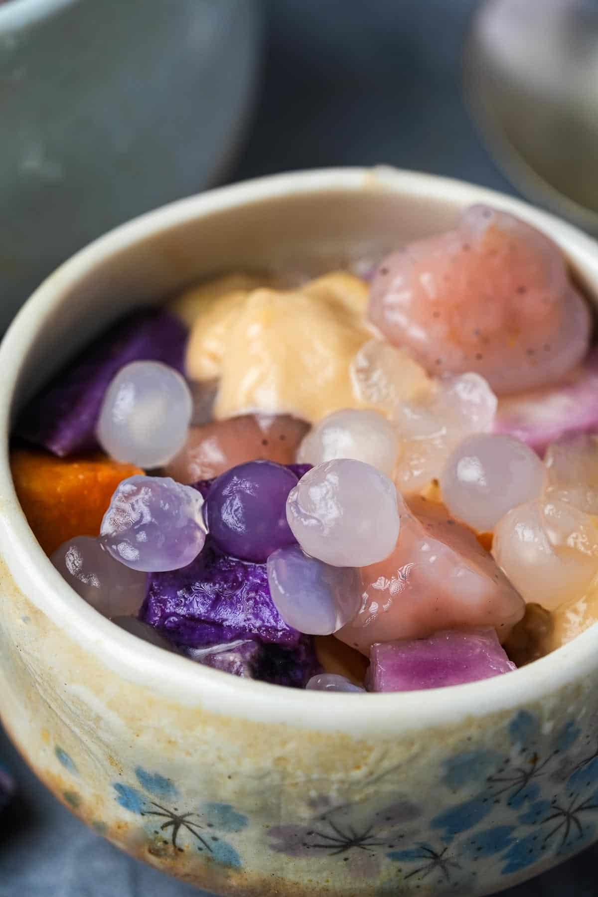 A bowl filled buber cha cha containing a variety of tapioca jellies, steamed root vegetables, and coconut porridge.