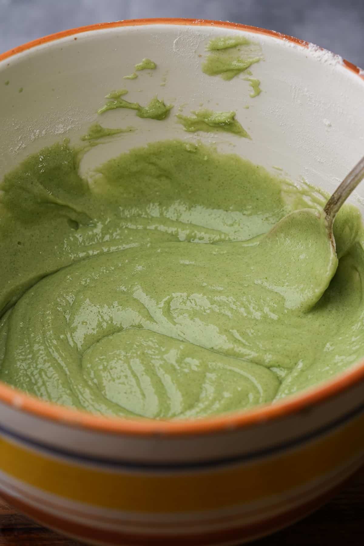 Pandan batter mixed up in a bowl with a spoon.