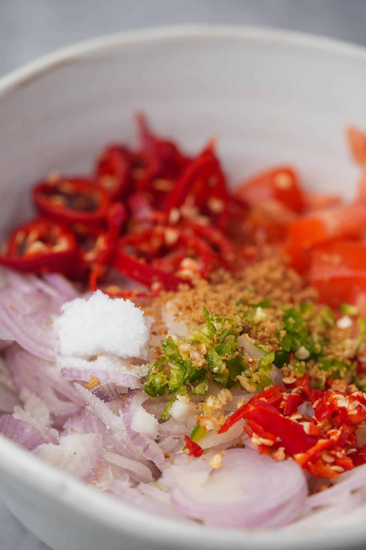 A bowl with shallots, peppers, and other ingredients.