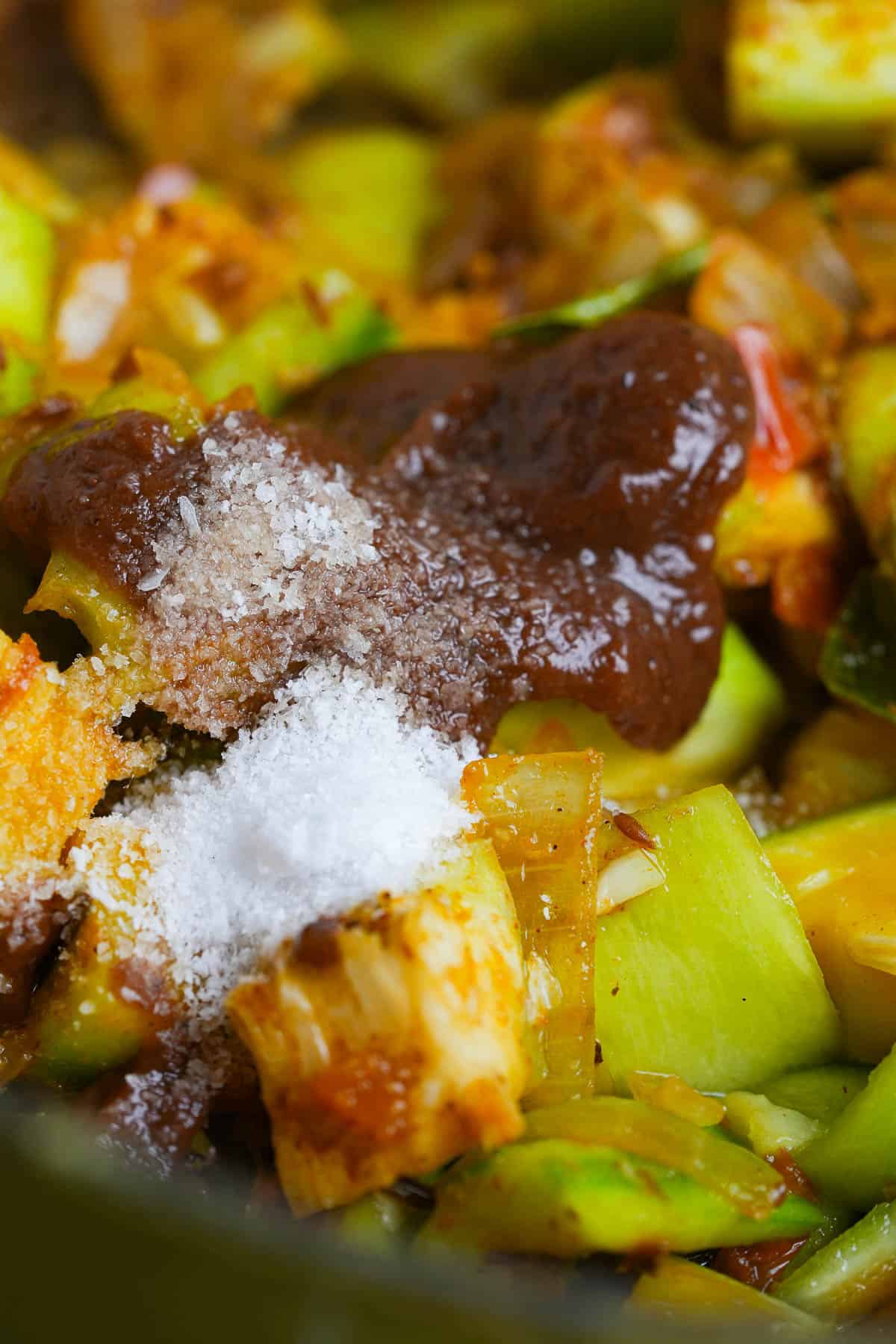 salt and tamarind concentrate are added to the cooking vegetables in a pan.