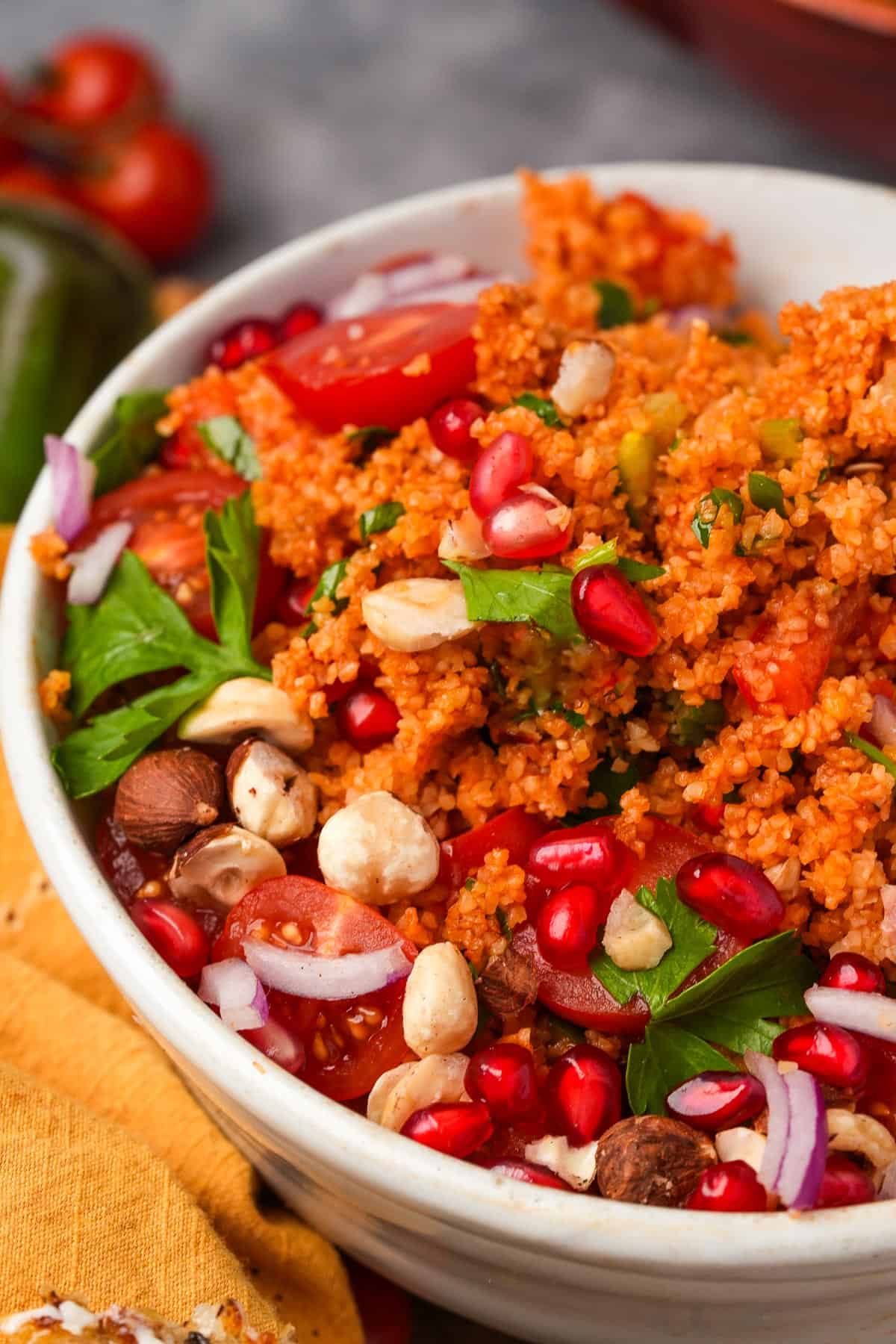 A bowl of kisir bulgur salad with tomatoes, herbs, and nuts.