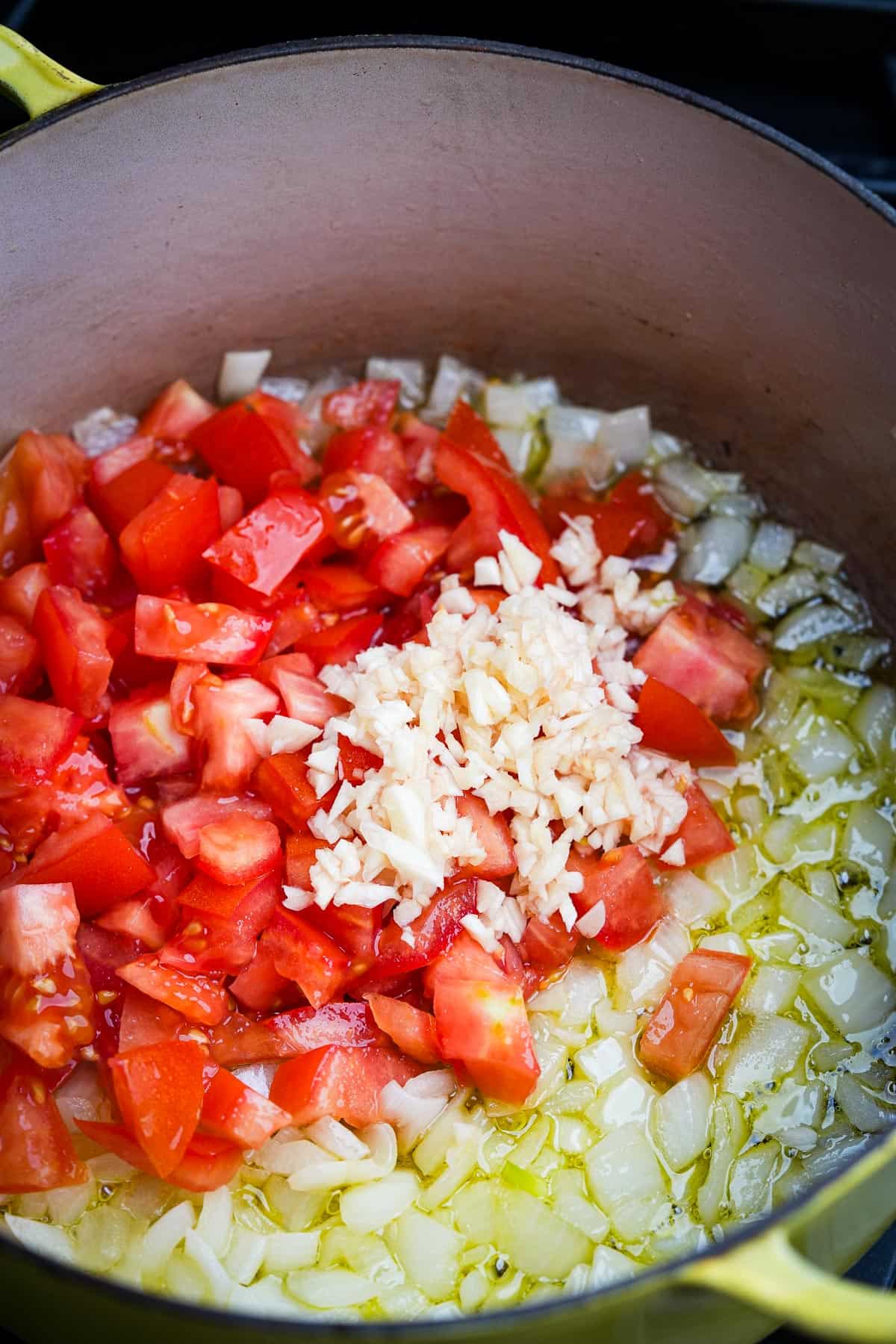 A pot with tomatoes, garlic and onions in it.