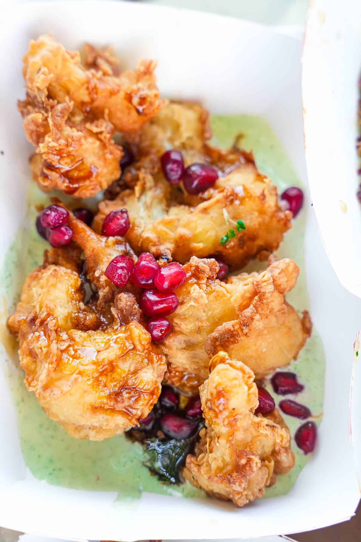 A plate of fried cauliflower with pomegranate sauce.