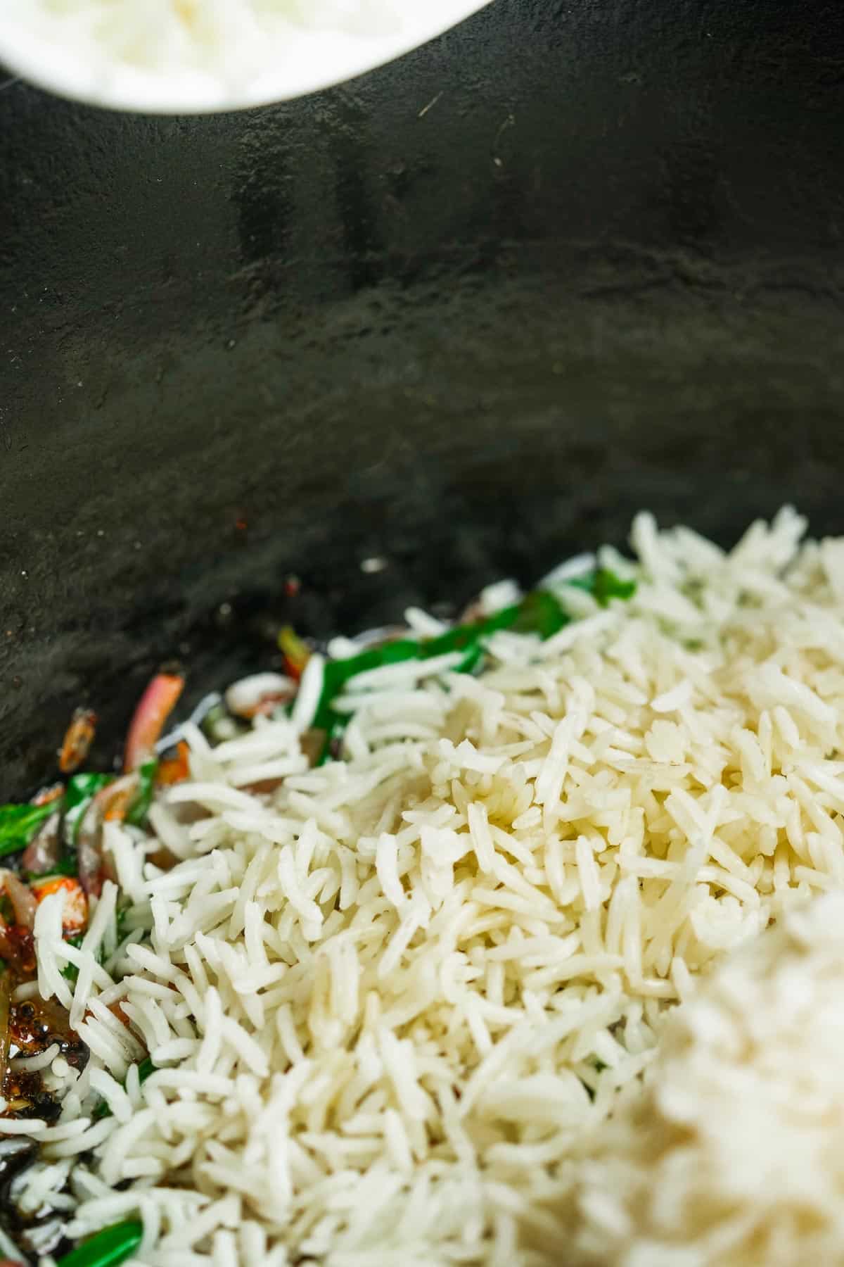 Rice is added to the stir-frying contents of the wok.
