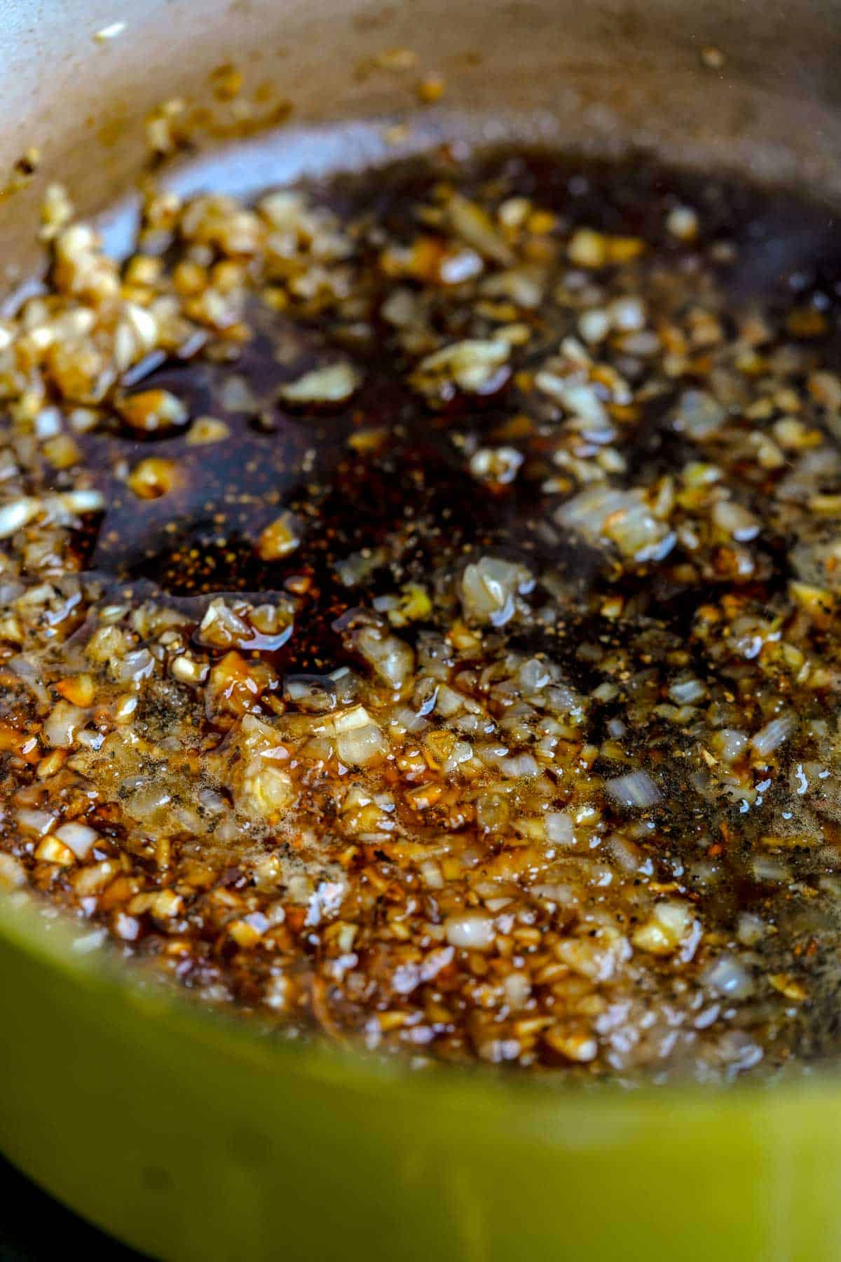Soy sauce mixture is added to the cooking onions and garlic in a pan.