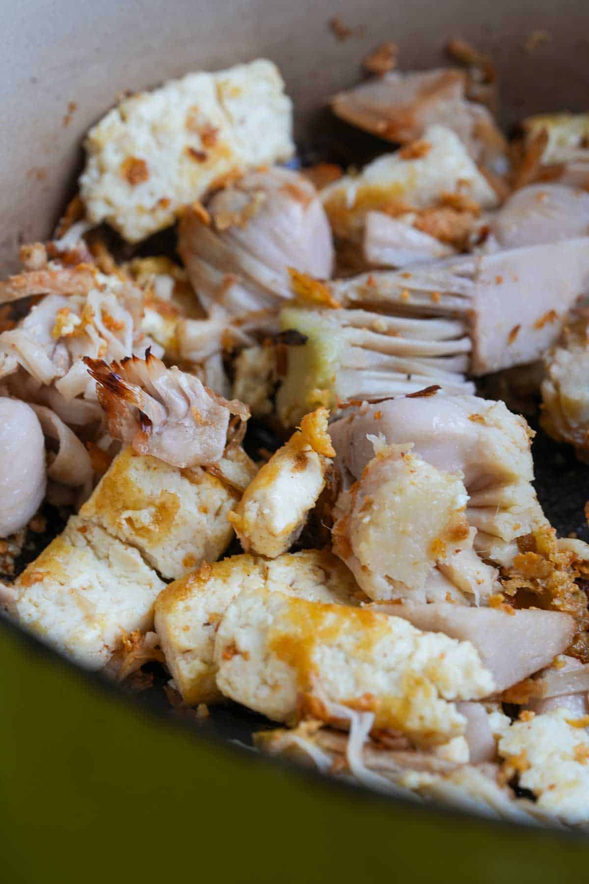 Jackfruit and tofu browning lightly in a pan.