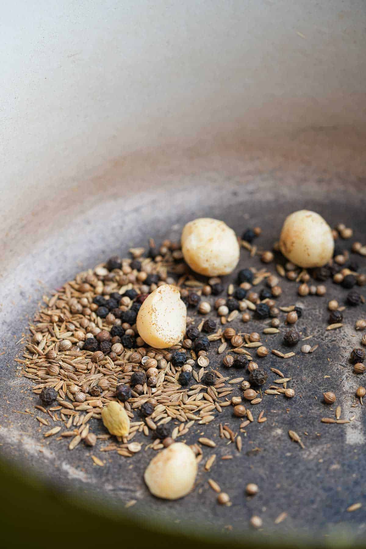 A frying pan with spices and nuts in it.