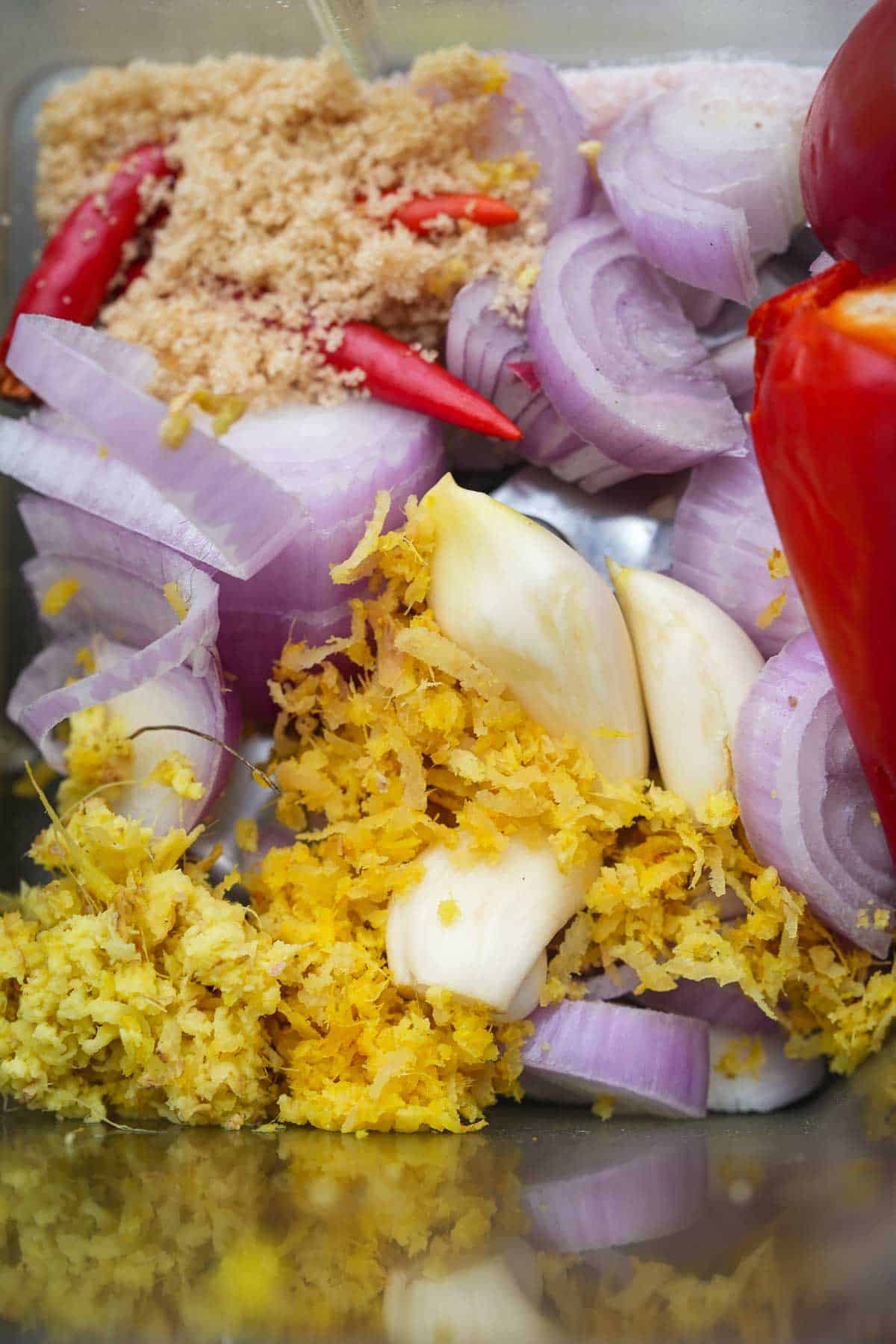 A blender filled with shallots, peppers, garlic, and other ingredients for making sambal.