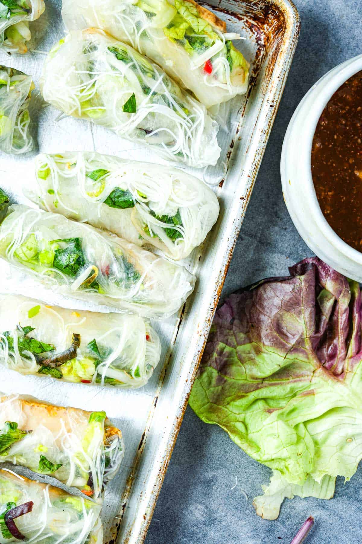 Vietnamese spring rolls on a baking sheet with dipping sauce.