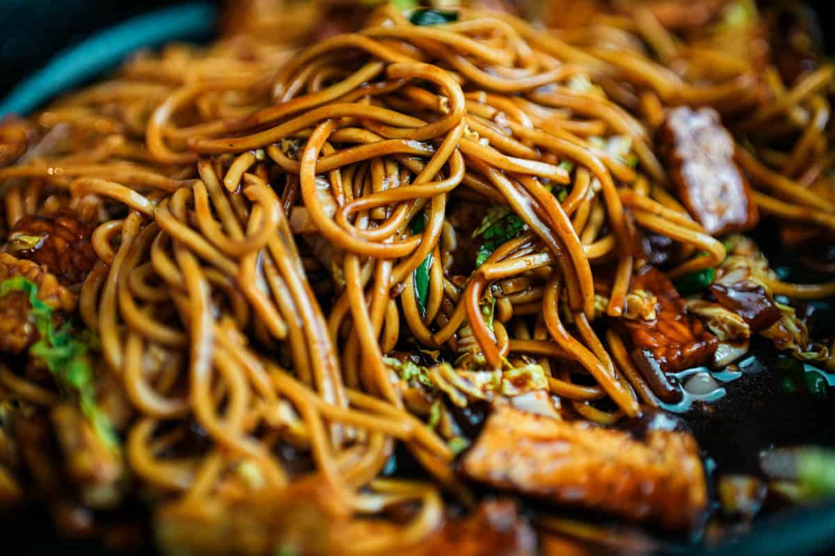 super close-up of juicy noodles being stir fried.