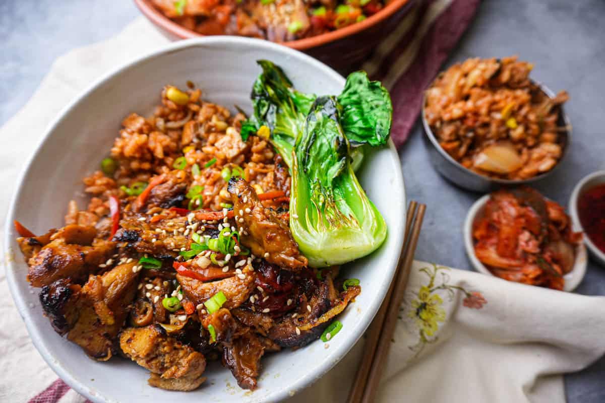 Vegan bulgogi with kimchi fried rice and steamed half of bok choy in a white bowl. Kimchi and chopsticks on the side.