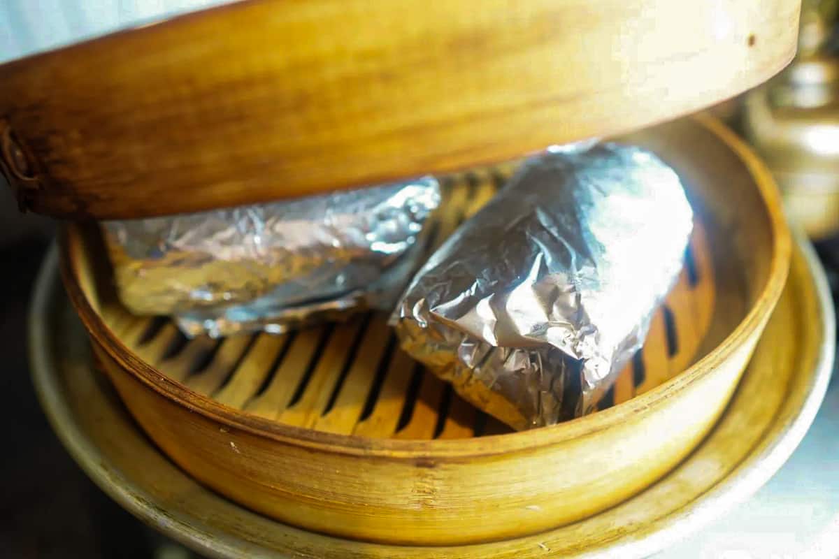 wrapped seitan in aluminum foil being steamed in a bamboo steamer.