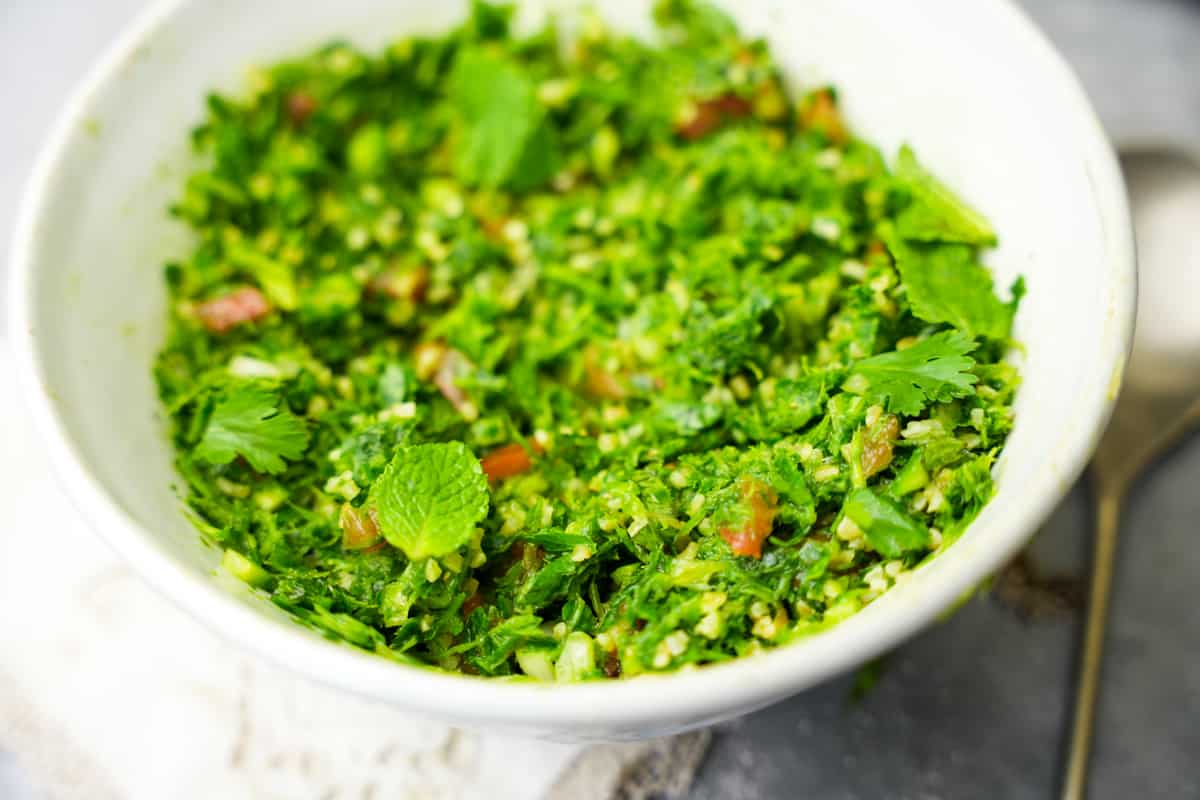 Taboule with bulgur garnished with mint in a wide white bowl.