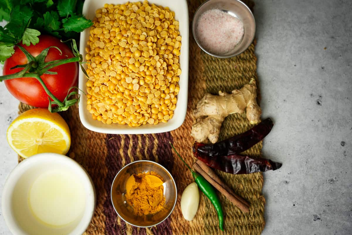 Arhar Dal ingredients measured out on a woven mat on a stone counter top.